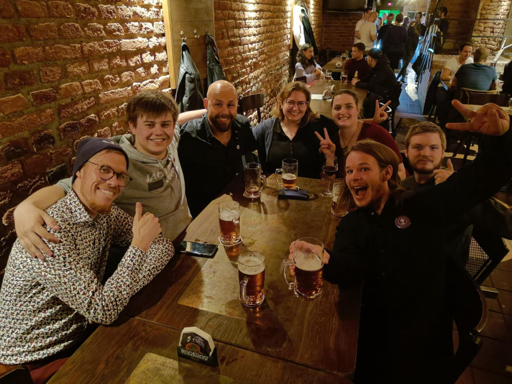 Bild einer Gruppe von Volt Mitgliedern bei einem Meet and Greet im Ruhrgebiet. Sie sitzen an einem Tisch mit Getränken und lächeln in die Kamera.