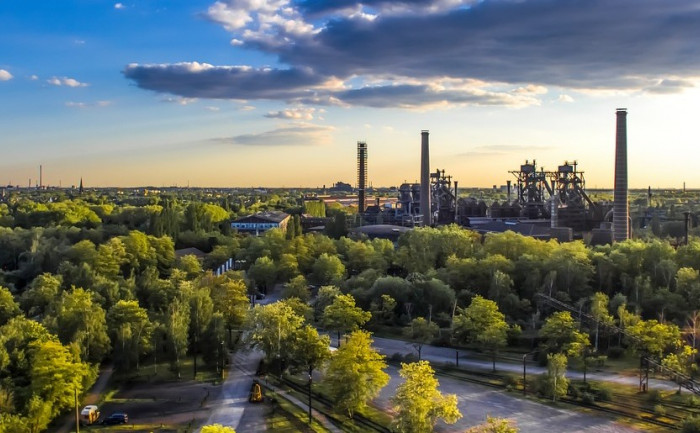 Blauer Himmel, darunter Industrieanlagen inmitten von Grün